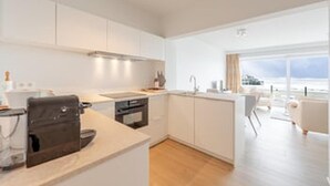 Una cocina moderna con armarios blancos, horno integrado y zona de comedor con vistas.