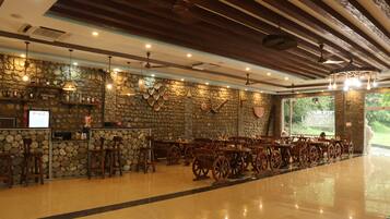 Un restaurante con pared de piedra, sillas y mesas de madera.