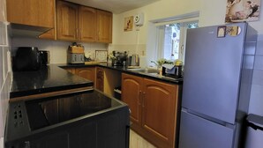 Una cocina con armarios de madera, lavavajillas negro, refrigerador y una ventana con vistas.