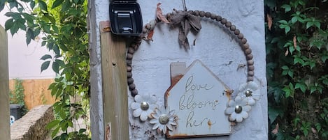 A rustic wooden post with a weathered sign that reads 'love blooms here' and a telephone.
