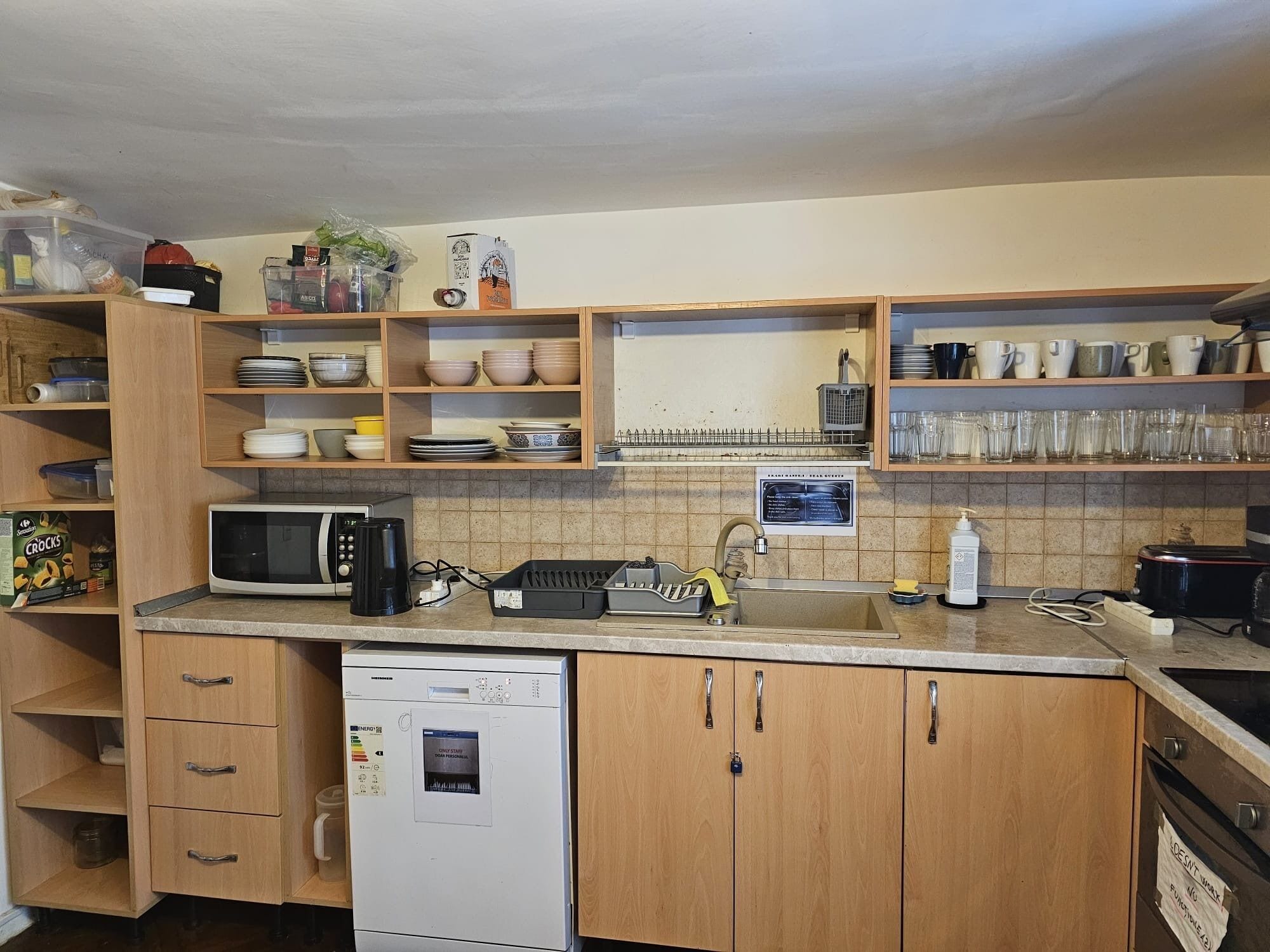 A kitchen with wooden cabinets, a dishwasher, a microwave, and various kitchenware.