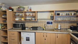 Une cuisine dotée de meubles en bois, d’un lave-vaisselle, d’un four à micro-ondes et de divers ustensiles de cuisine.