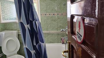 A bathroom with a white toilet, a bathtub, and a shower curtain.