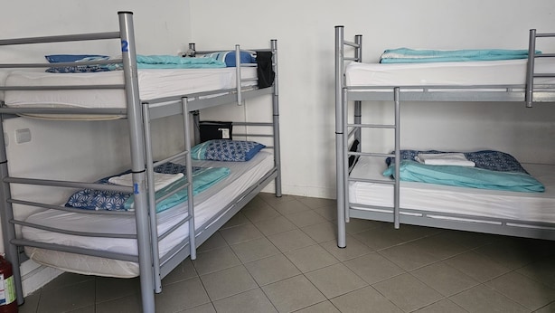 Une chambre de dortoir avec des lits superposés, un extincteur et un mur blanc.