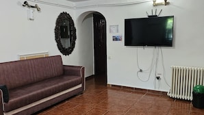 Un salon comprenant un canapé, une table basse, un téléviseur fixé au mur et un radiateur.