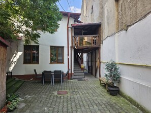 A courtyard with a staircase leading to a wooden balcony, surrounded by buildings. - Hostel Sport Bucharest (Bucharest)