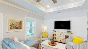 A living room with a sofa, armchair, and a TV mounted on the wall. - Days at the Beach | Pet Friendly | PCB (Panama City Beach)