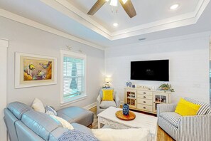 Ein Wohnzimmer mit einer Couch, einem Sessel und einem an der Wand befestigten Fernseher.