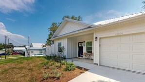 A single-story house with a garage, a front porch, and a small garden area. - Days at the Beach | Pet Friendly | PCB (Panama City Beach)