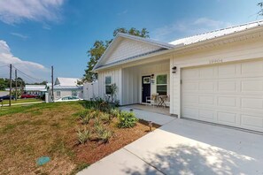 Ein Bungalow mit Garage, einer Veranda und einem kleinen Garten.