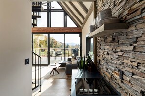 A modern interior with a stone wall, a staircase, and a view to the outdoors. - The Lakeside Cabin at Arete (Page County)