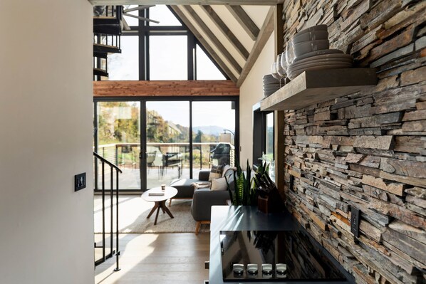Ein modernes Interieur mit einer Steinwand, einer Treppe und Blick ins Freie.