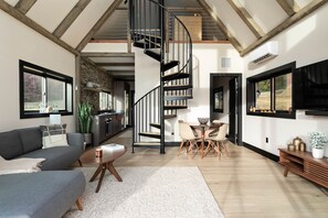A modern interior with a spiral staircase, a dining area, and a living room with a sofa and coffee table. - The Lakeside Cabin at Arete (Page County)