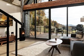 A modern interior with a fireplace, a sofa, a table, and a view of the outdoors. - The Lakeside Cabin at Arete (Page County)