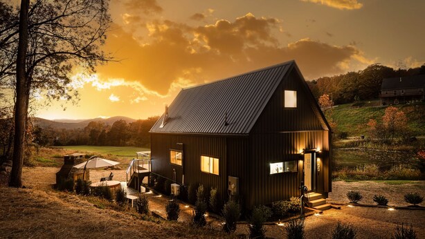 A rustic cabin with a sloped roof, a front porch, and a small deck. - The Lakeside Cabin at Arete (Page County)