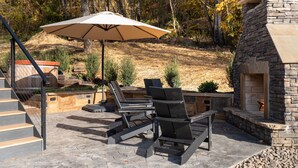 A patio with outdoor furniture, a stone fireplace, and a staircase. - The Lakeside Cabin at Arete (Page County)