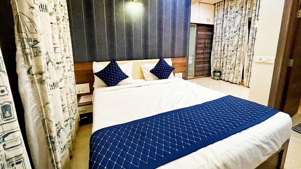 Une chambre d’hôtel avec un lit, des rideaux, une tête de lit et une porte.