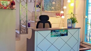 Un comptoir d’accueil avec une pancarte indiquant « RÉCEPTION », une plante en pot et un guichet d’enregistrement.