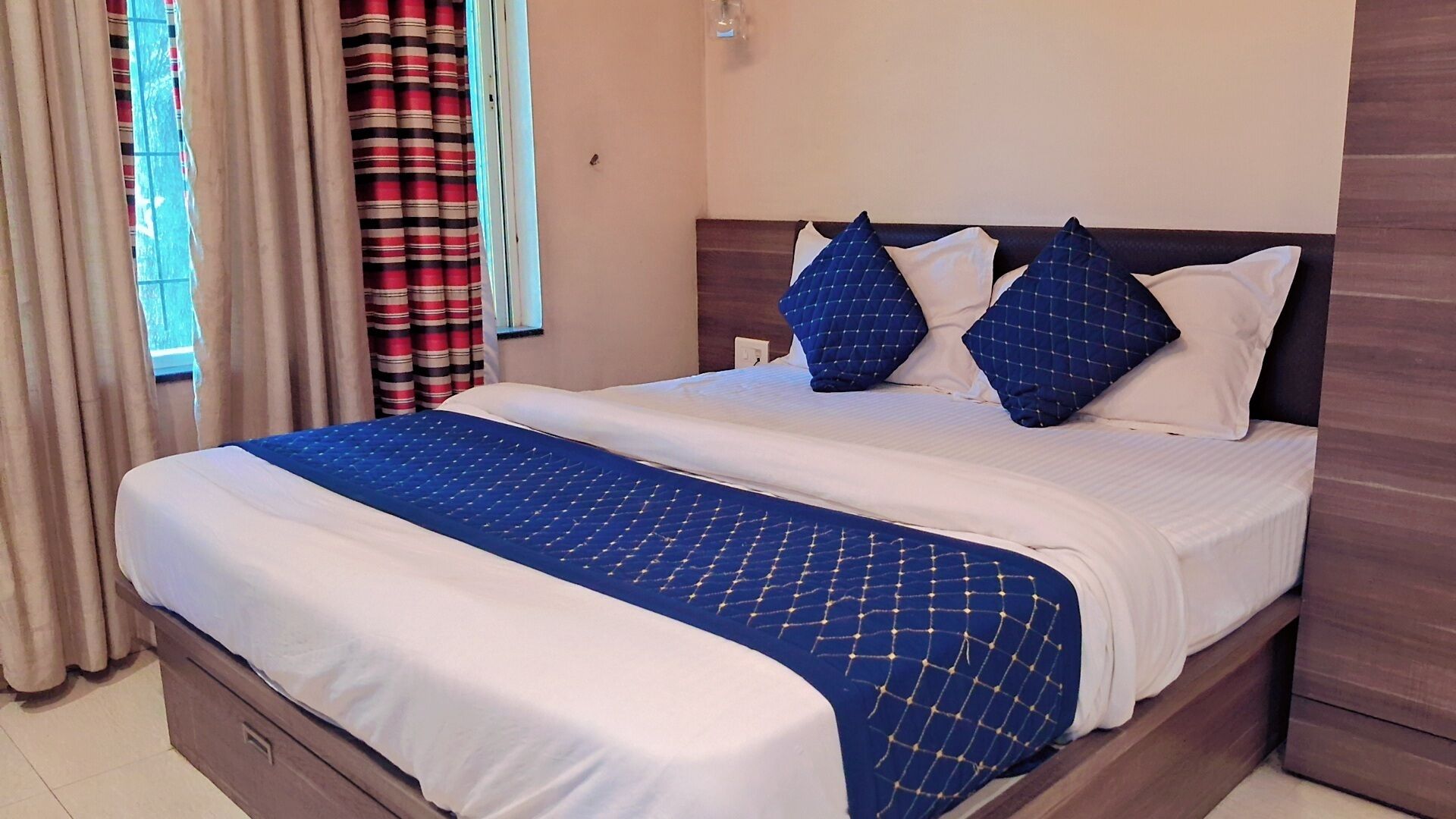 A hotel room with a bed, curtains, and a window.