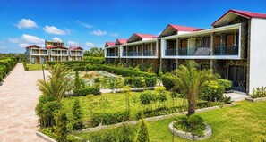 A hotel with multiple-story buildings, a landscaped garden, and a clear sky. - Corbett  River Heart  Resort (Ramnagar)