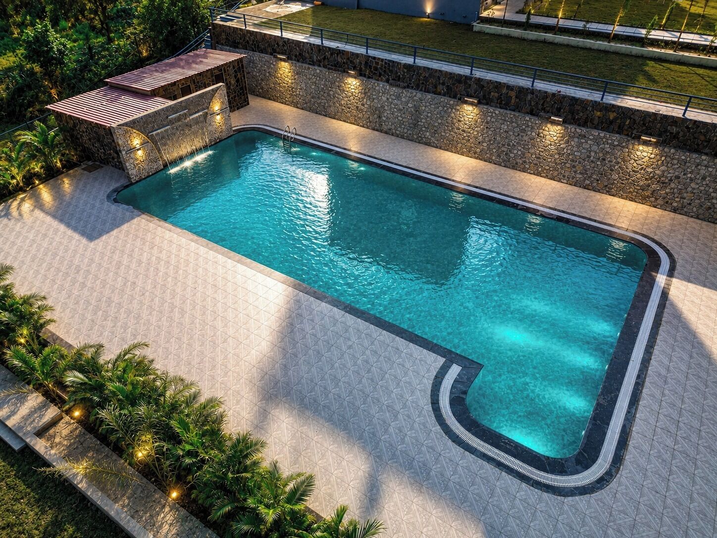 A rectangular swimming pool with a stone border and a tiled deck area.