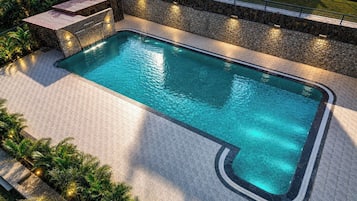 A rectangular swimming pool with a stone border and a tiled deck area.