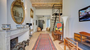 Ein Wohnzimmer mit Kamin, einem großen Spiegel, einer Treppe und einem Bild an der Wand.
