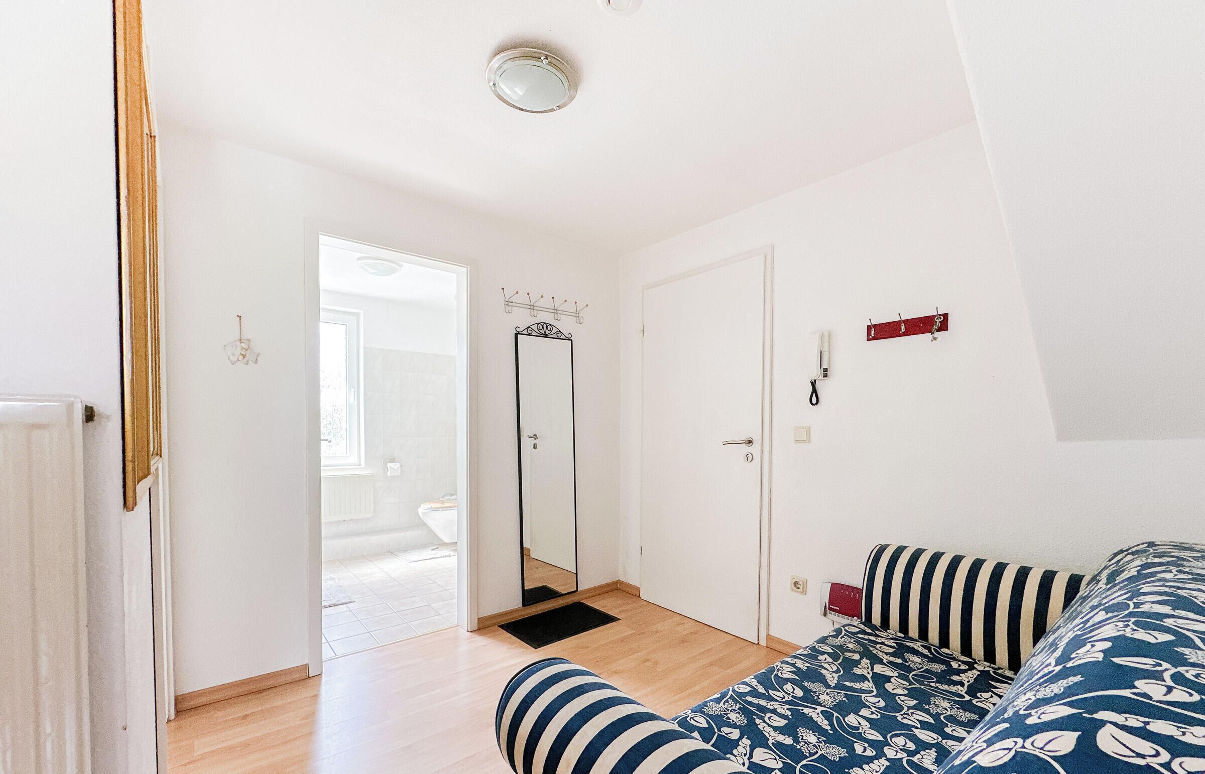 A bedroom with a bed, a mirror, a wardrobe, and a door leading to another room.