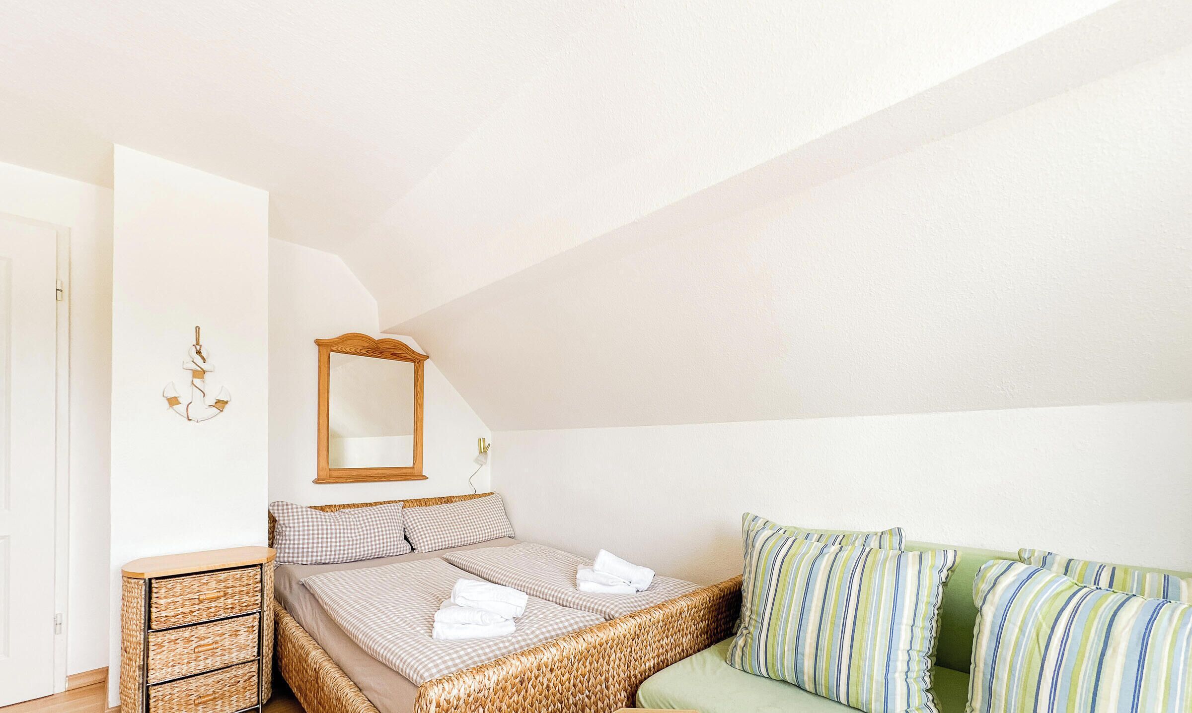 A bedroom with a bed, a dresser, a mirror, and a green sofa.
