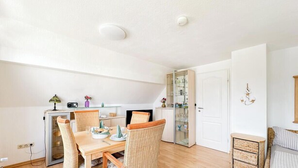 Een eetruimte met een tafel, stoelen, een kast met glazen deuren en een witte deur.
