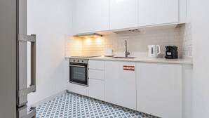 Cuina compacta amb armaris blancs, forn encastat, cafetera i torradora.