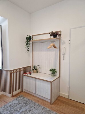 A corner room with a built-in desk, a hanging plant, a small potted plant, a wooden hanger, and a door. - Charming one-bedroom apartment near Belém, Lisbon (Lisboa)