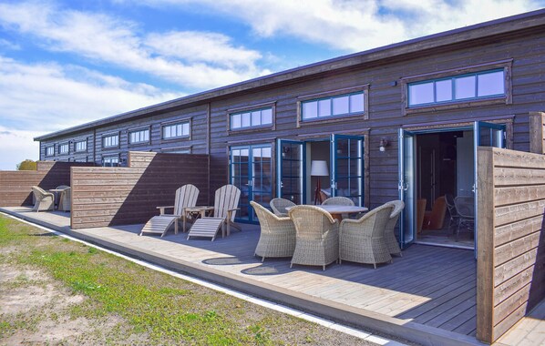 A wooden building with a deck, outdoor seating, and a large window. - Gorgeous home in Kivik with WiFi (Kivik)