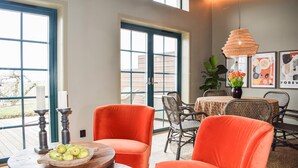 A dining area with orange chairs, a round table with a bowl of fruit, and a hanging light fixture. - Gorgeous home in Kivik with WiFi (Kivik)