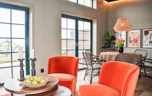 A dining area with orange chairs, a round table with a bowl of fruit, and a hanging light fixture. - Gorgeous home in Kivik with WiFi (Kivik)