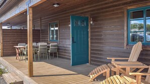 A wooden cabin with a teal door, outdoor seating, and a view of the surrounding area. - Gorgeous home in Kivik with WiFi (Kivik)