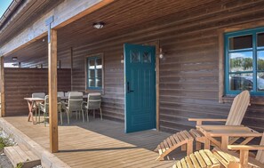 A wooden cabin with a teal door, outdoor seating, and a view of the surrounding area. - Gorgeous home in Kivik with WiFi (Kivik)