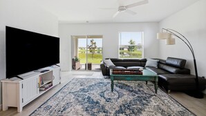 Ein modernes Wohnzimmer mit Flachbildfernseher, ledernem Sofa, Couchtisch und großem Teppich.