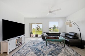 Ein modernes Wohnzimmer mit Flachbildfernseher, ledernem Sofa, Couchtisch und großem Teppich.