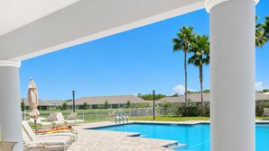 Ein überdachter Außenbereich mit Pool, Liegestühlen und einem Tisch.