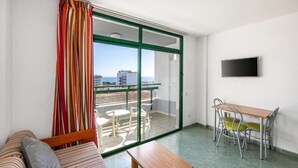Un balcón con vistas a la ciudad, una zona de comedor con sillas y una mesa, y un sofá con cojines.