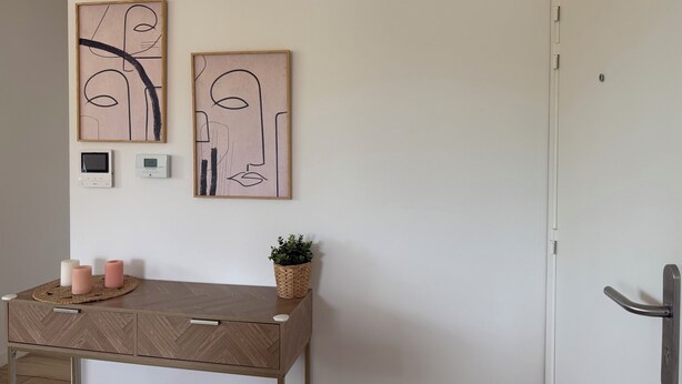 Una habitación con un escritorio de madera, dos termostatos en la pared y una obra de arte abstracta.