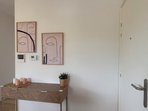A room with a wooden desk, two wall-mounted thermostats, and abstract art. - Appartement premium 2 chambres au cœur de Seignosse, plage accessible en vélo (Seignosse)