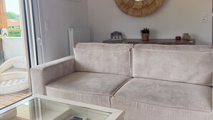 Un salón con un sofá a rayas, un espejo redondo, una mesa de centro de vidrio con objetos decorativos y un mapa enmarcado en la pared.