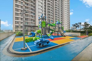 Ein Spielplatz mit Rutschen und Klettergeräten, umgeben von einem Hochhauswohngebäude.