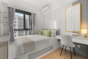 Un dormitorio moderno con cama, escritorio, silla y un espejo grande.