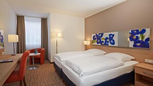 Ett hotellrum med en säng, ett skrivbord, en stol och en lampa.