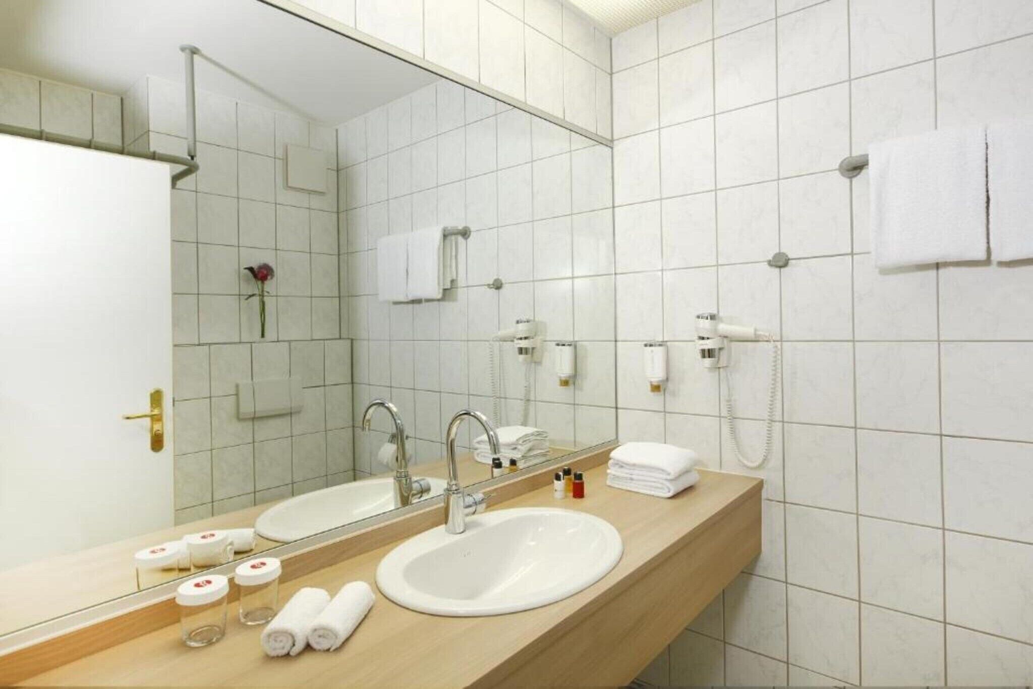 Un baño de hotel con dos lavamanos, un espejo grande y un perchero para toallas.