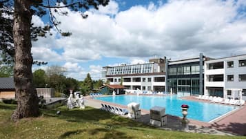 Et hotel med swimmingpool, liggestole og en bygning med flere etager.