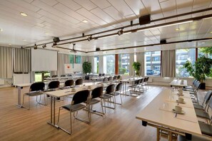 A conference room with multiple tables and chairs, large windows, and ceiling-mounted projectors. - Sunday Hotel des Norden deluxe double room (Harrislee)